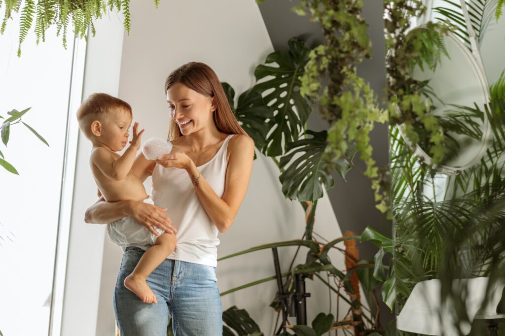 Smiling mother is giving baby bubble bath