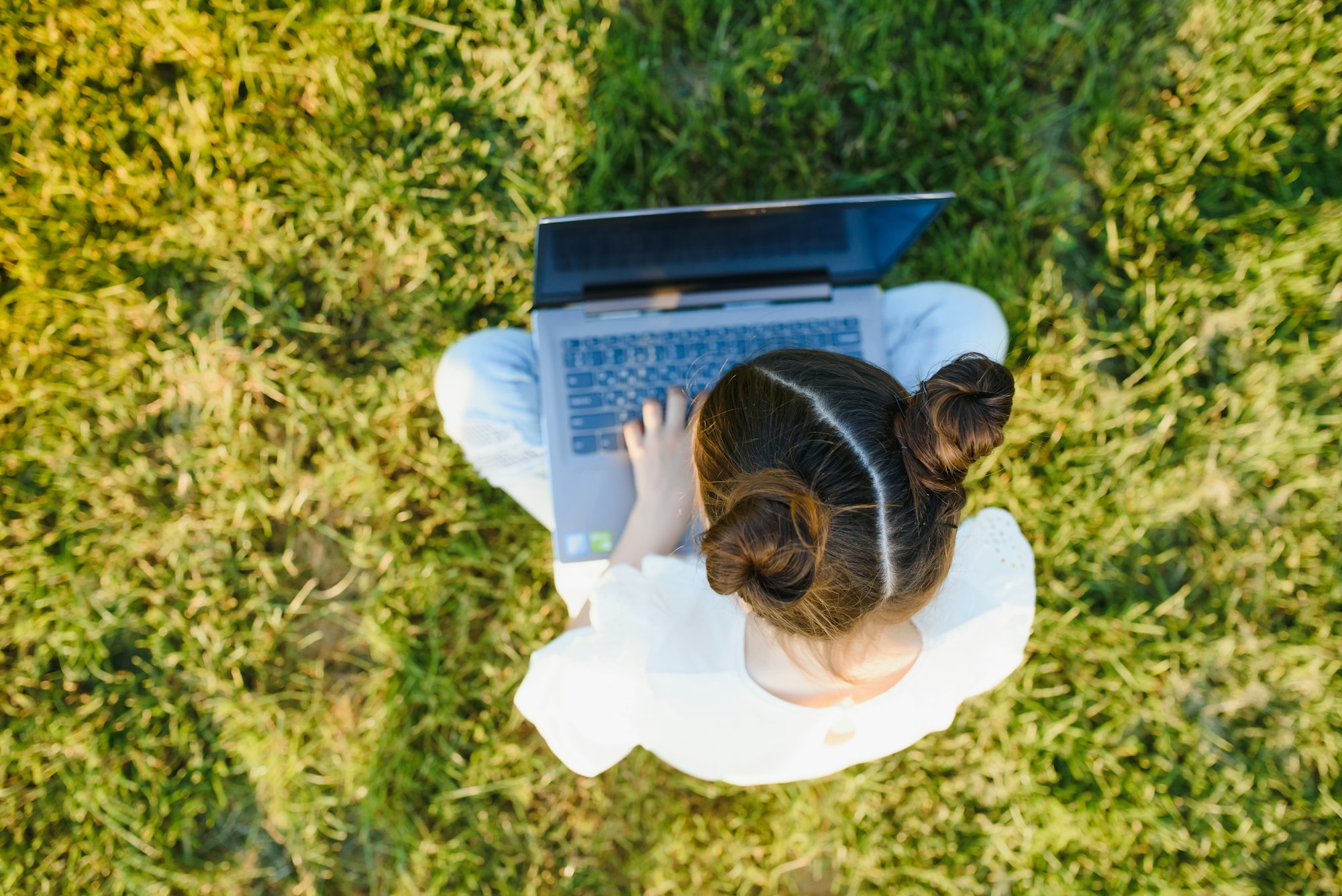 little girl play computer on green grass