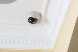 Vista ravvicinata di una telecamera di sicurezza a cupola, montata su un soffitto con decorazioni eleganti e rifinite, pronta a monitorare l'area circostante.
