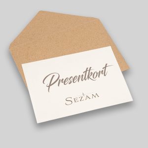 Foto av ett öppnat brunt kuvert med ett kort ovanpå med texten: "presentkort, sezam"