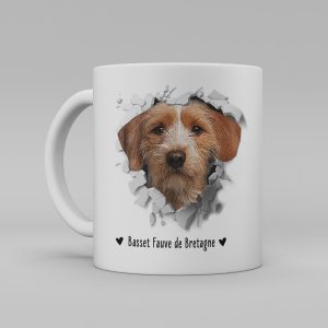 Vit keramikmugg med illustration av ett hundhuvud som "tittar ut genom" ett illustrerat hål. Hunden är av rasen Basset Fauve de Bretagne