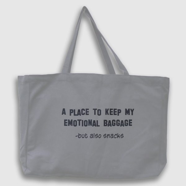 Foto på en grå tygväska med svart text på engelska: "A place to keep my emotionel bagage, but also snacks"