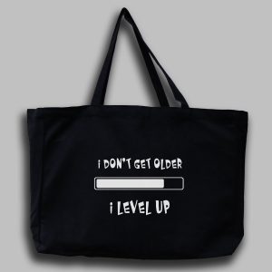 Svart tygväska med vit engelsk text: "I don't get older I level up"