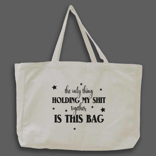 Naturvit tygväska med svart text på engelska: "the only thingholding my shit together is this bag"