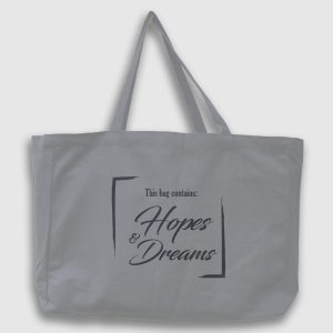 Foto på grå tygväska med svart text på engelska: "This bag contains hopes & dreams"