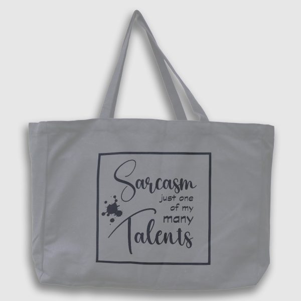 Foto på grå tygväska med svart text på engelska: "Sarcasm Just one of my many talents"
