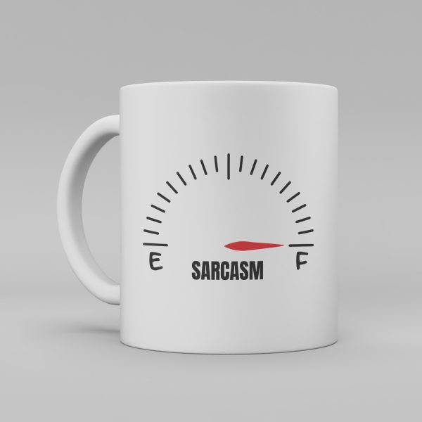 Vit keramikmugg med svart text: "Sarcasm" Ovanför ordet finns en illustration som ser ut som en mätare där röd pil visar att mätaren är full.