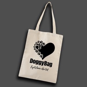 foto på naturvit tygkasse med konturer av ett hjärta i helsvart, del av hjärtat har flertal tassavtryck. Under hjärtat står texten: "DoggyBag". Under "Eget namn eller text"