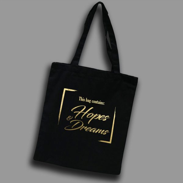 Svart tygkasse med guldtext på engelska: "This bag contains hope & dreams"