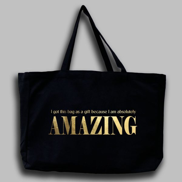 Foto av svart tygväska med guldfärgad text på engelska: "i got this bag as a gift because i am absolutly amazing"