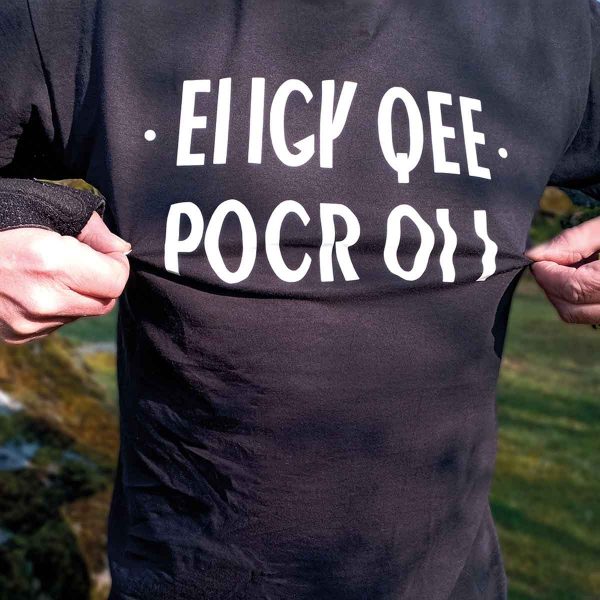 Foto på svart t-shirt med vit text: "EIIGY QEE POCR OII"