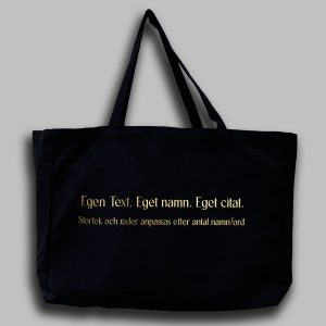 Foto av en svart tygväska med guldtext: "egen text eget namn eget citat, Storlek och rader anpassas efter antal namn/ord "