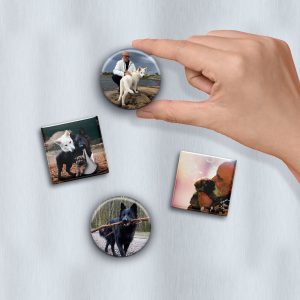 Närbild på en hand som sätter upp en rund fotomagnet på en kylskåpsdörr. På dörr sitter ytterligare 1 rund fotomagnet och 2 kvadratiska.