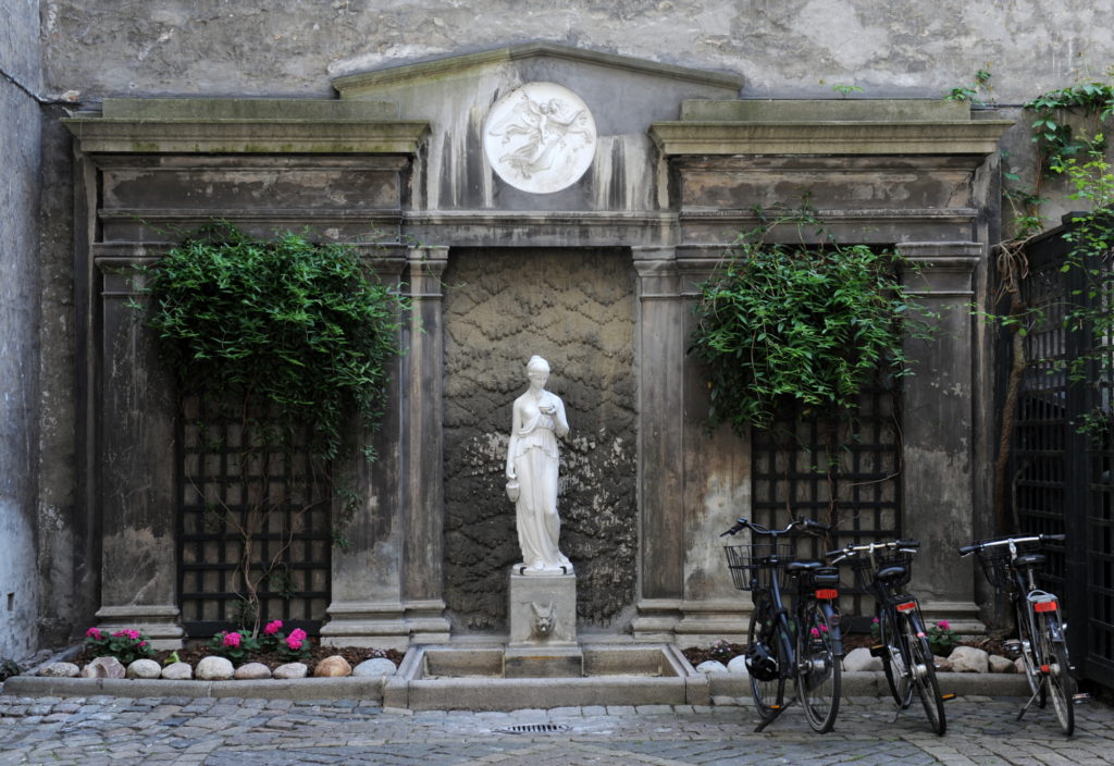 Skulptur af marmor foran facade formet som forsiden af et antik tempel