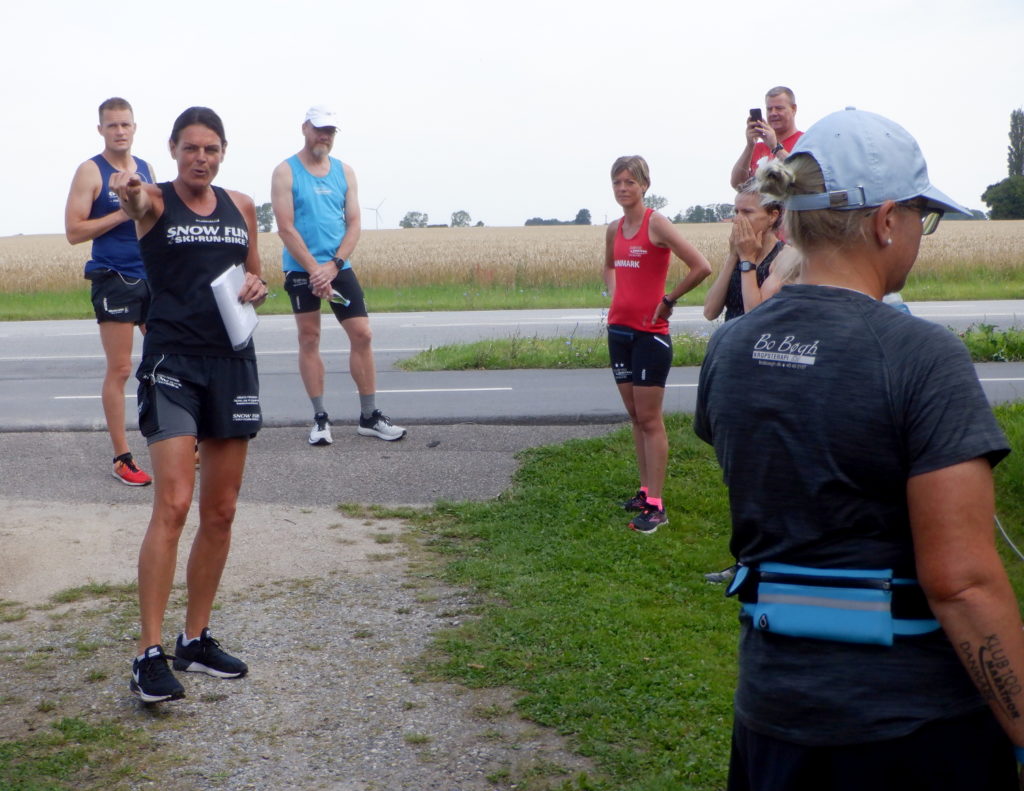 Kvinde omgivet af andre løber der lytter til hendes forklaring