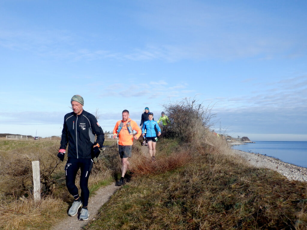 Løbere på et spor langs stranden og havet