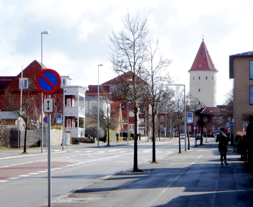 Bygade. Bag husene for ende af vejen ses et hvidt vandtårn. Ser man godt efter kan man spotte et par løbere på billedet.