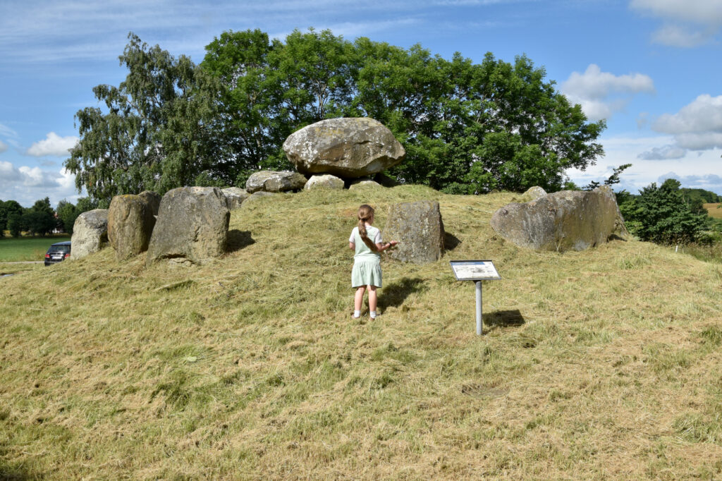 Flot rundhøj med dysse og randsten. En pige beskuere monumentet