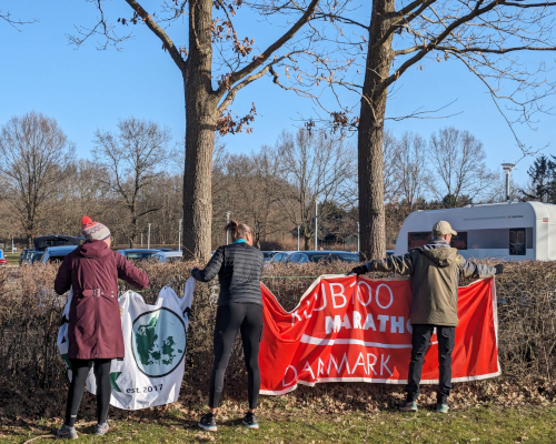 Tre personer forsøger at hænge et banner op.