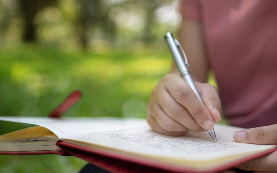 poet writing on notebook in park