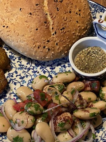 Bord met Turkse bonensalade, brood, falafel en sumak dressing