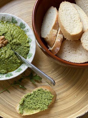 Een schaaltje rucola pesto met een walnoot en een schaal met stokbrood