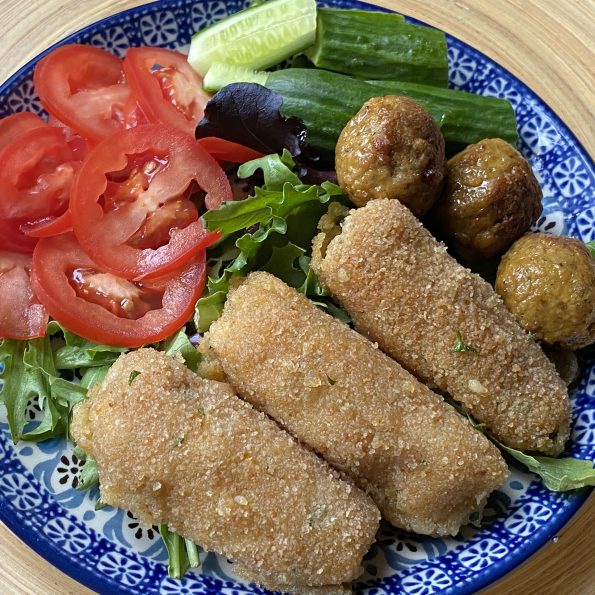 Bord met salade, aardappelkroketjes en vegan balletjes