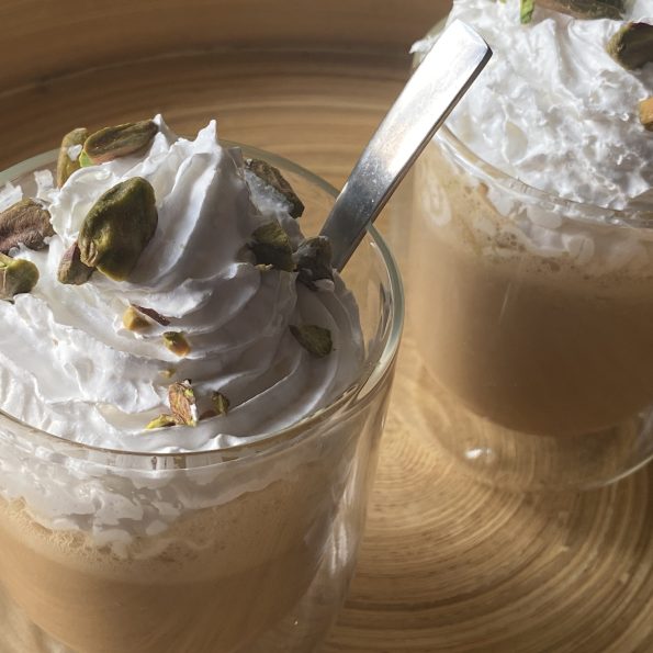 Twee glazen met pistache frappucino, slagroom en gehakte pistachenootjes