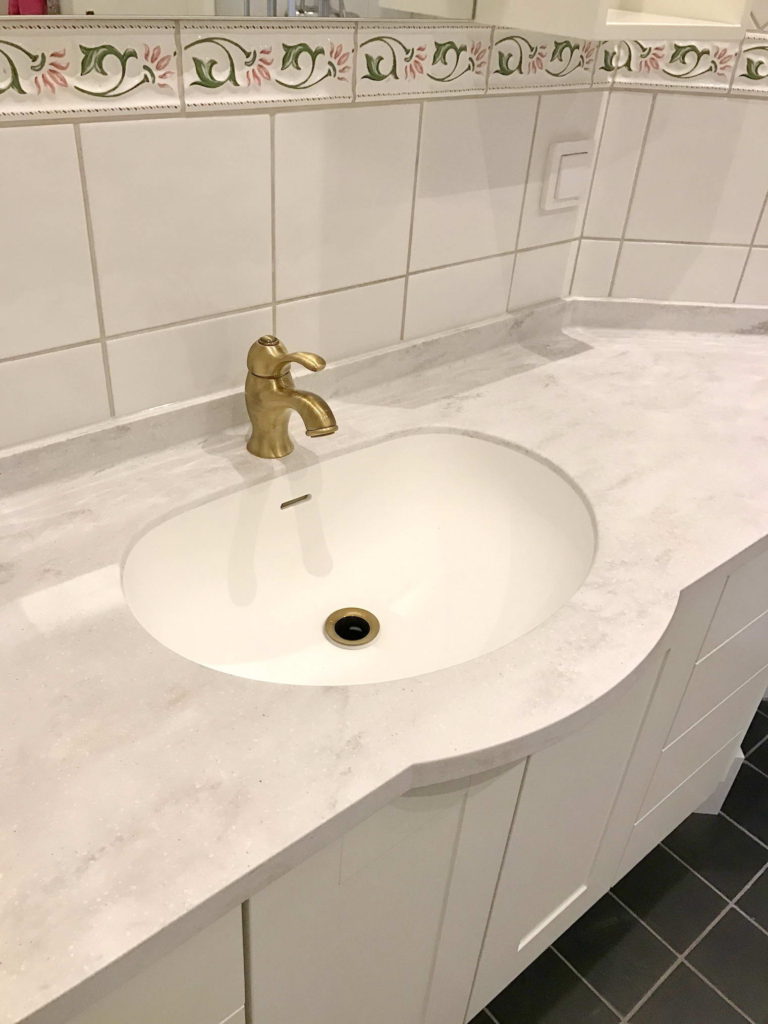 Badrumsinredning med bänk och integrerat tvättställ i Corian®