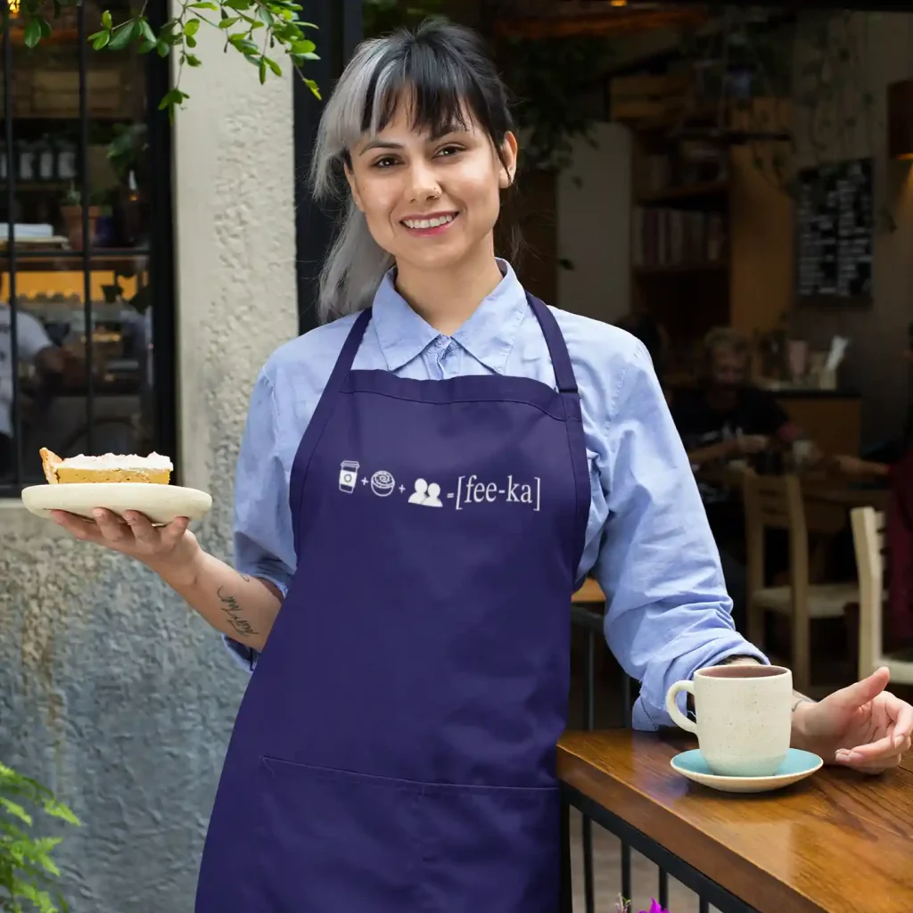 Woman wearing a dark blue apron with Fika Rebus print