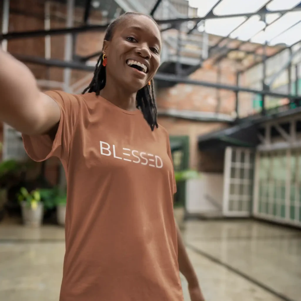 Girl wearing a terracotta Bella-Canvas t-shirt with white Blessed print