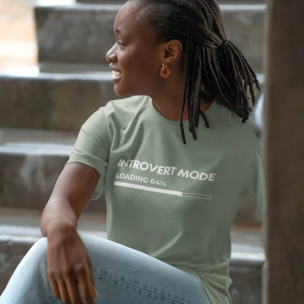 Young woman wearing a sage green Bella-Canvas t-shirt with white Introvert Mode print