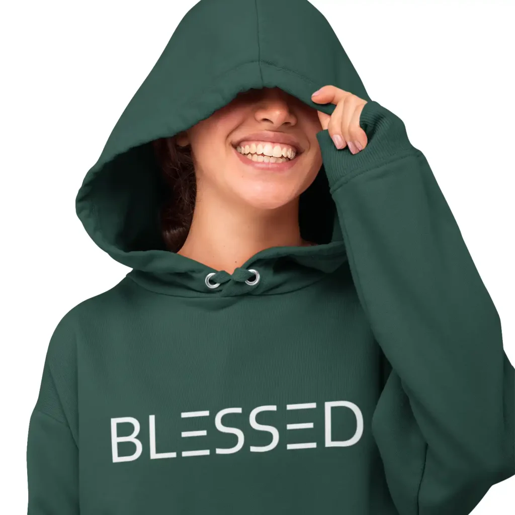 Young woman wearing a forest green hoodie with white Blessed print