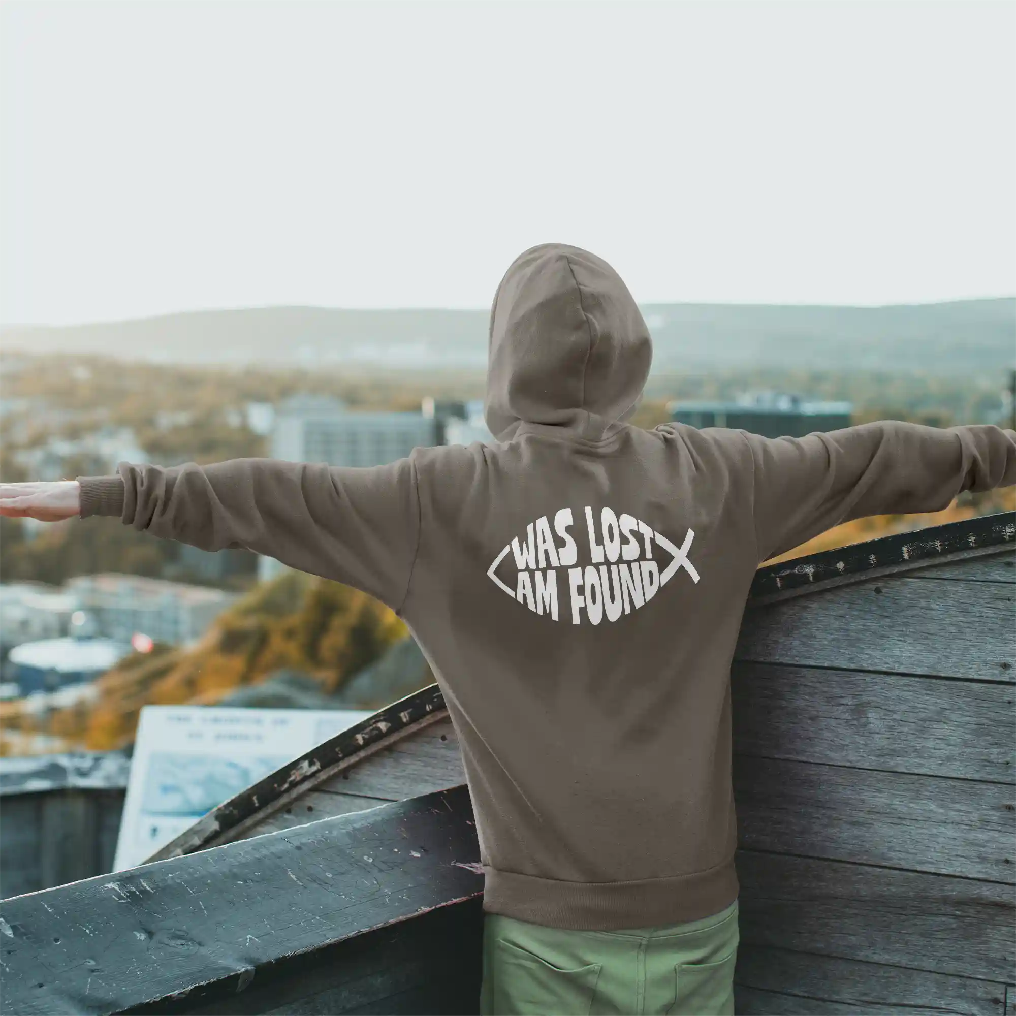 Man wearing a mocha Just Hoods hoodie with white Found print on the back