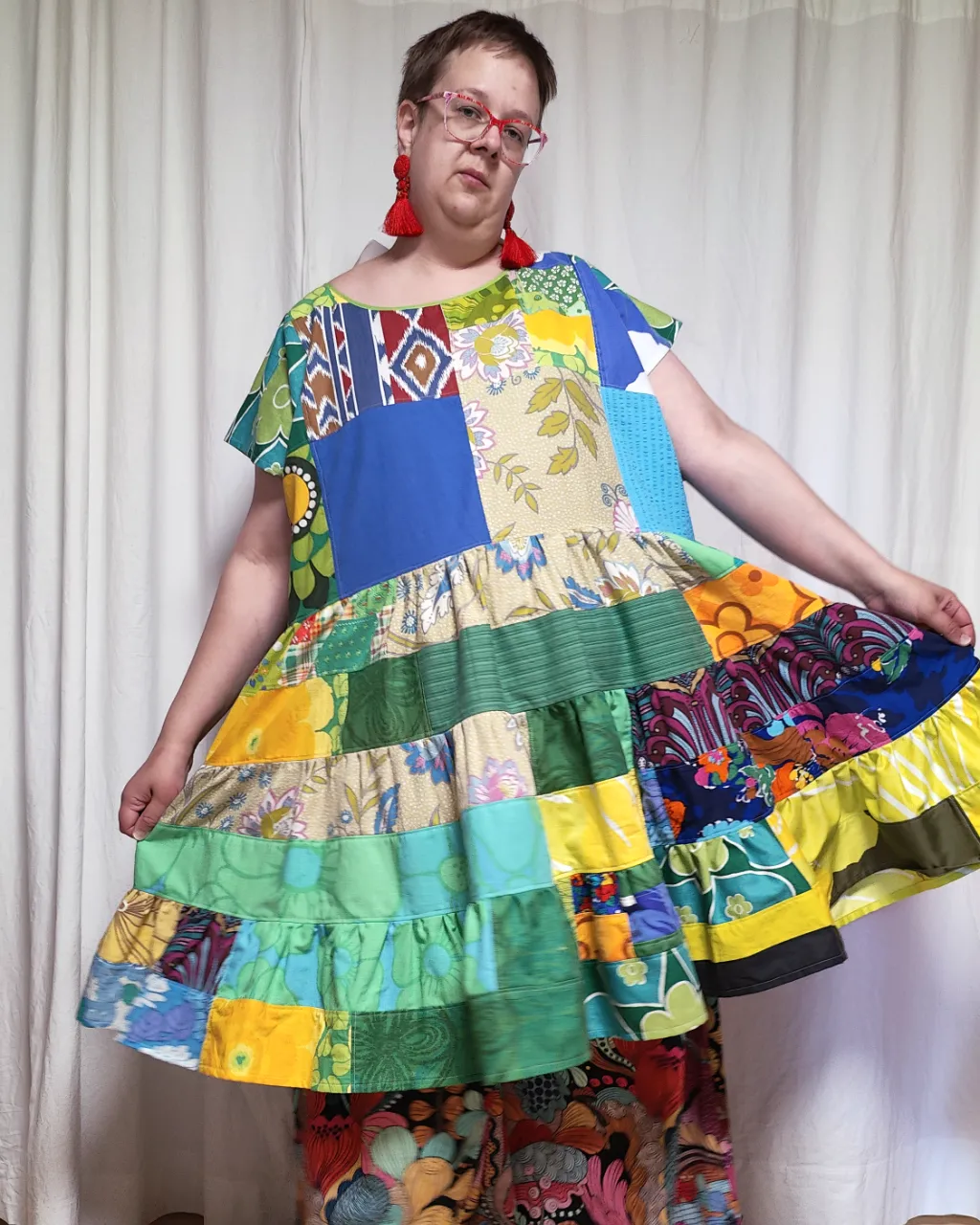 Medelålders tjock kvinna i en färgglad midiklänning i patchwork i gröna och blå färger sydd av slow fashion-företaget Skamlös Design
