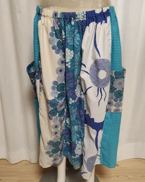 Kjol i patchwork med blå och gröna färger. Bomull. Kjolen sitter på en kläddocka. Kjolen är sydd av slow fashion-företaget Skamlös Design