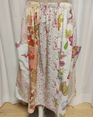 Kjol i patchwork med vit och beige ochmönste ri rosa samt orange. Bomull. Kjolen sitter på en kläddocka. Kjolen är sydd av slow fashion-företaget Skamlös Design