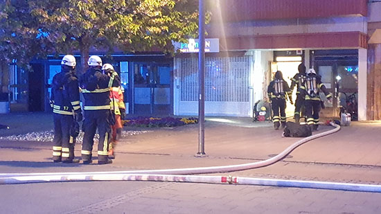 Brandmän går in i byggnaden vid Stora Torget, Tibro