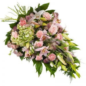 Begravningsbukett med blommor i rosa; lilja, nejlika, rosor, prärieklocka, astrantia och säsongsgrönt. Finns hos Euroflorist.