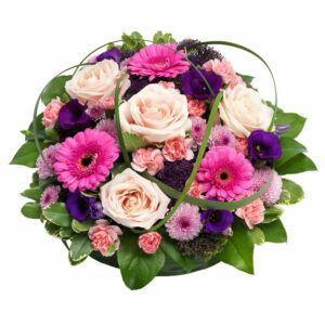 Rund begravningsdekoration, här med blommor i rosa, cerise och lila. Begravningsdekorationen finns att beställa online hos Euroflorist.