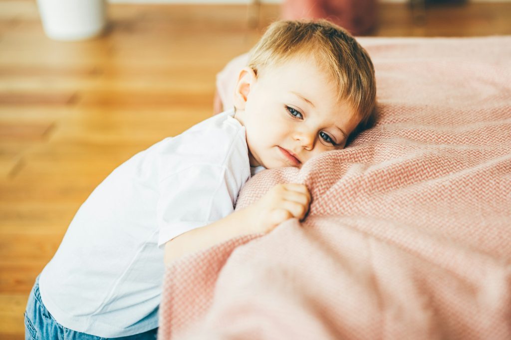 Tired child standing near the bad.