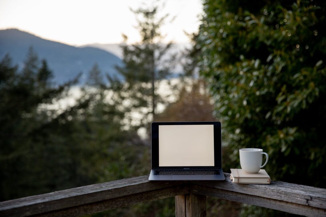 laptop with blank screen and cup of hot drink