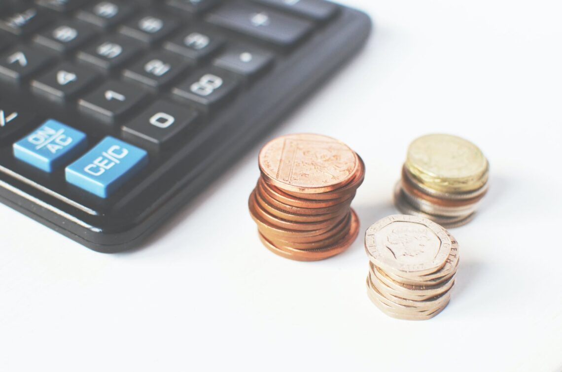 gold colored coins near calculator