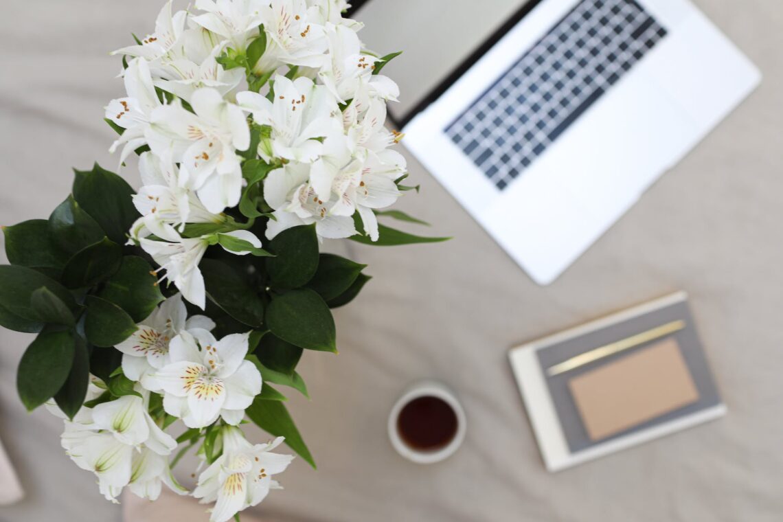 bouquet of lilies placed near laptop and notebook
