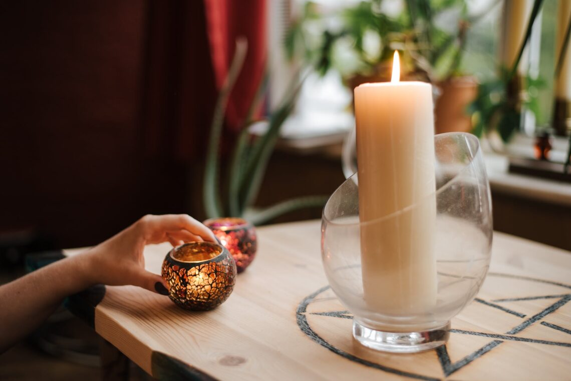 crop fortune teller near shiny candles at table at home