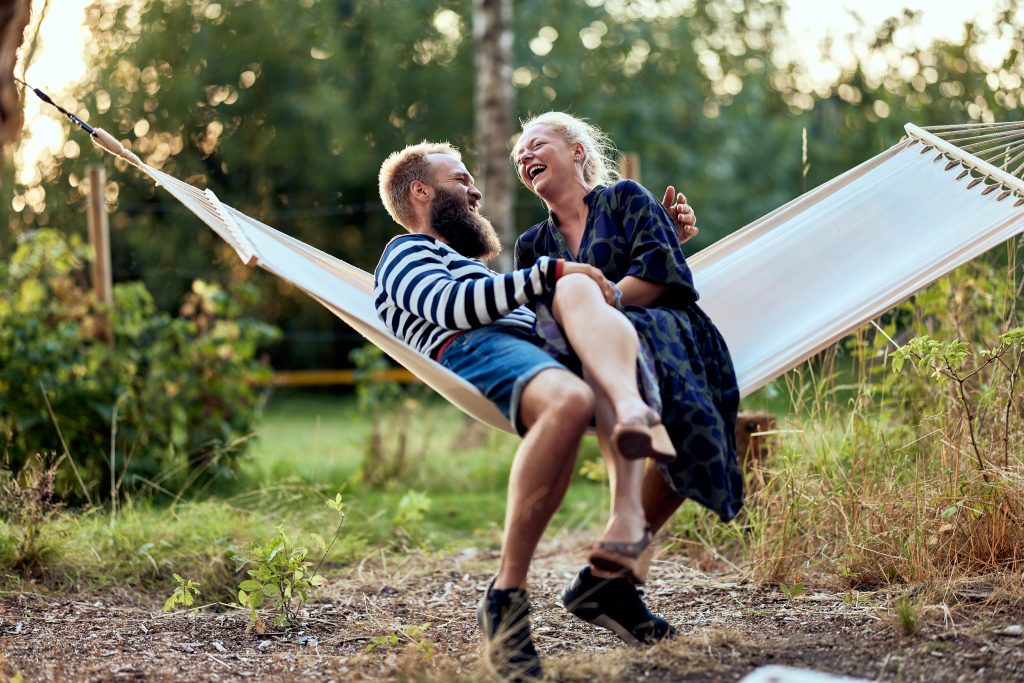 Couple laughing together on a hammock on a late afternoon in summer