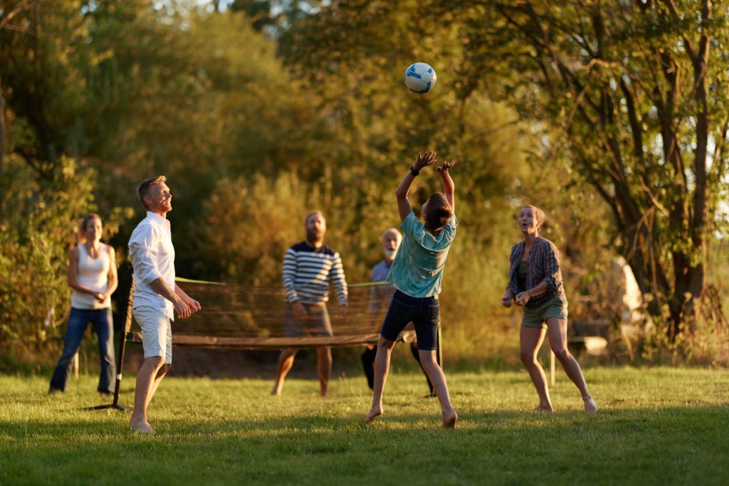 Family and friends playing volleyball together outside on a sunny afternoon in summer