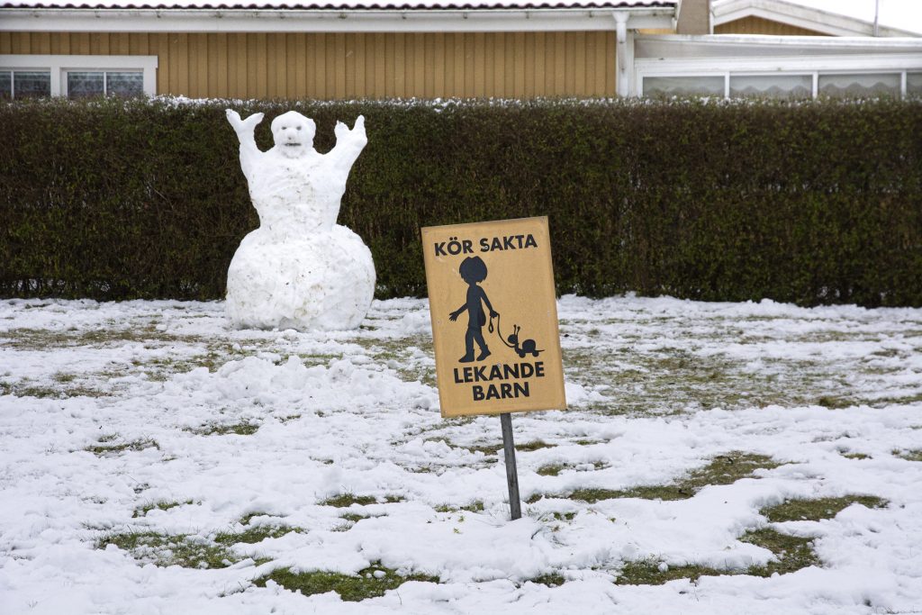 Snögubbe och skylt som säger !Lekande barn!.