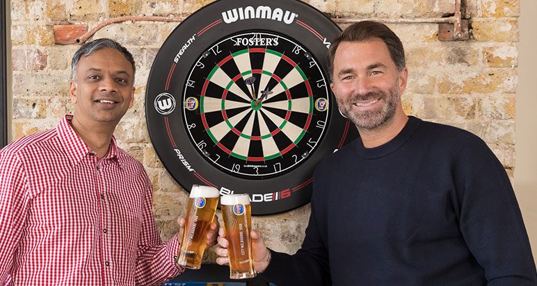 Men holding pints before a dartboard