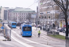 Mitt i trafikkorsningen står en trafikledare och dirigerar kollektivtrafiken.